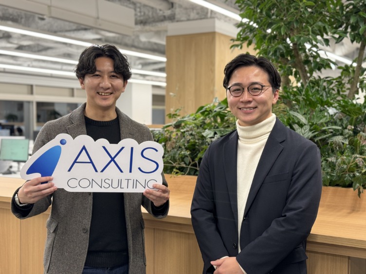 アクシスコンサルティング株式会社のロゴを手に持つ長谷部さんと隣に立つ遠藤さん