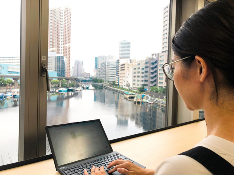 株式会社BookLiveの社内で窓際の席に座った女性がPC作業をしている様子