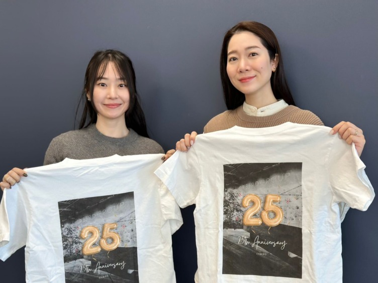 株式会社サイバードの根本さんと川尻さんが25周年のTシャツを持っているようす