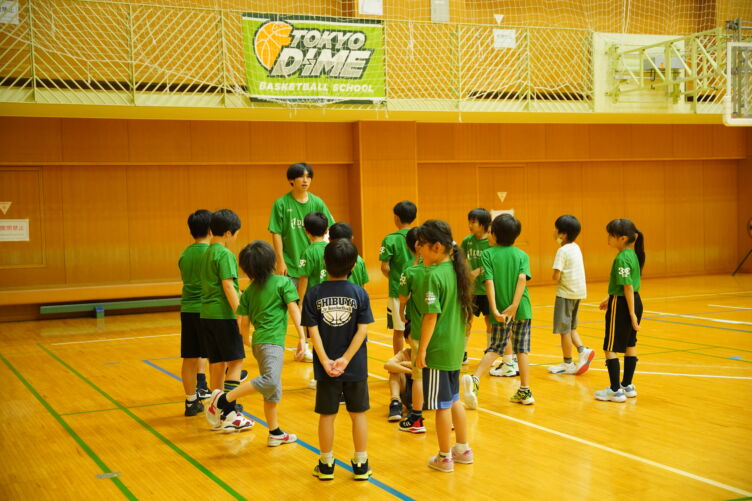 バスケスクールで現役選手でもあるコーチが子どもたちに教える様子