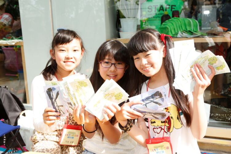 一般社団法人ユメ・フルサトが発行する「おむすび通貨」を両手にいっぱい持つ少女たち