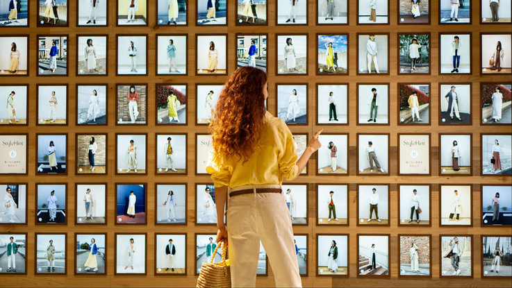 I＆COがプロデュースしたユニクロの次世代型店舗「StyleHint原宿」で商品イメージを見る女性
