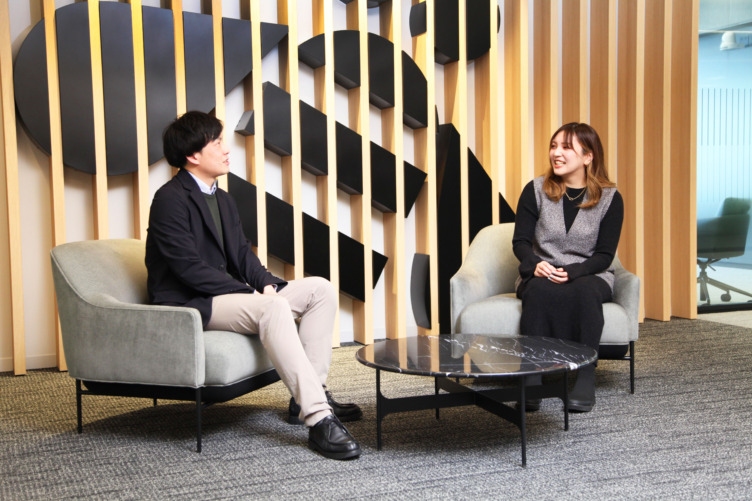 日本アイ・ビー・エムデジタルサービス株式会社のオフィスのソファで談笑する佐竹さんと戸塚さん