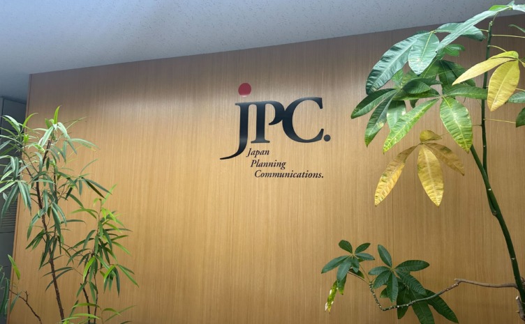 株式会社ジェー・ピー・シーのロゴが壁面に掲示されている社内風景