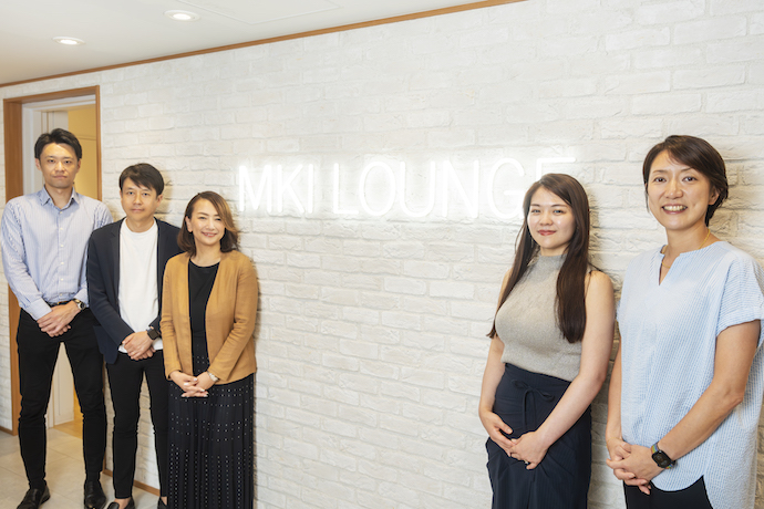 三井情報株式会社の東中野オフィス内「MKI LOUNGE」のエントランスに集まる社員の方々